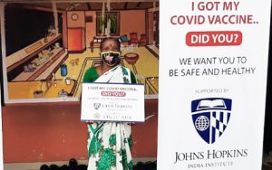 A masked woman holding an "I got vaccinated" sign