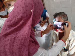 A woman takes a photo of a patient's eye with a cell phone app